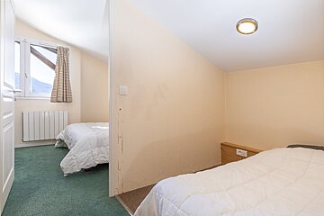 A small bedroom with two beds and a window