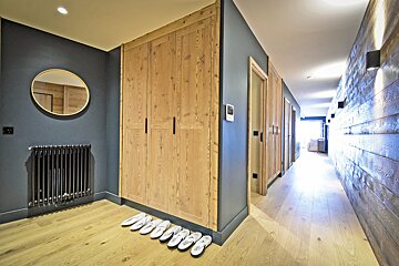 A hallway with wooden cabinets and slippers on the floor