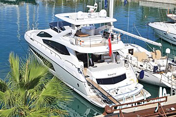 A large white yacht named reef v is docked in a marina