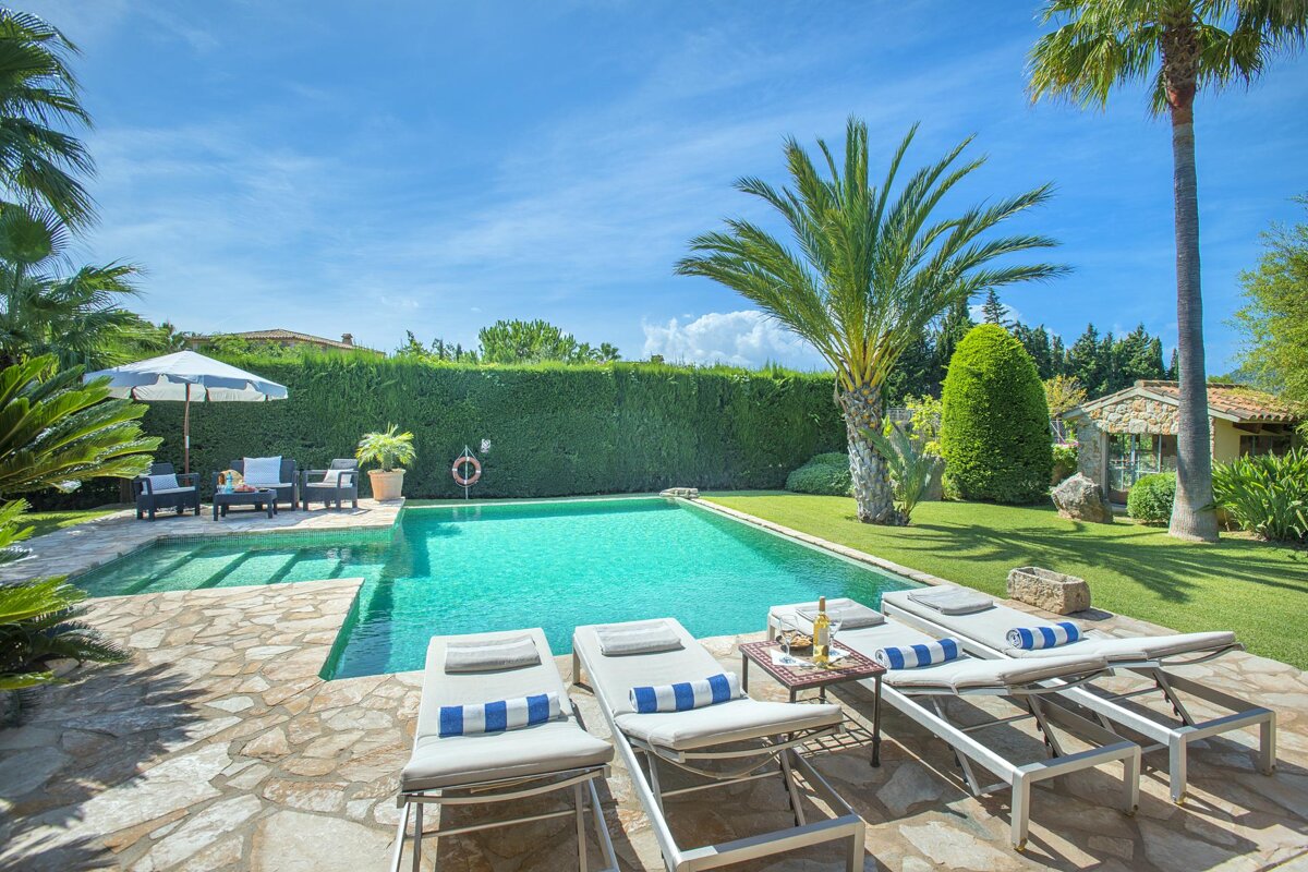A swimming pool surrounded by lawn chairs and a white umbrella