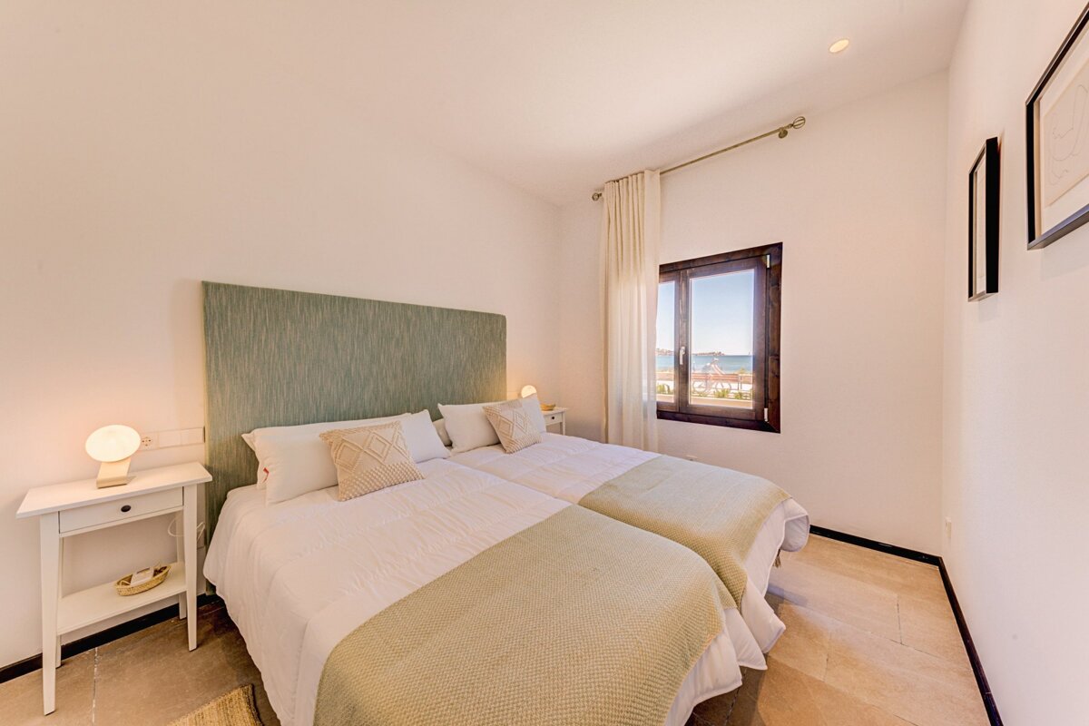 A bedroom with two beds and a window with a view of the ocean