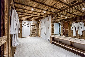 A wooden hallway with robes hanging on hooks and a large mirror