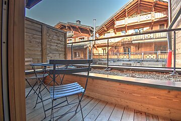 A wooden balcony with a table and chairs
