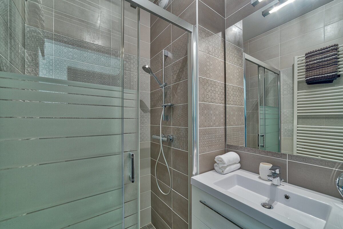 A bathroom with a sliding glass shower door and a sink