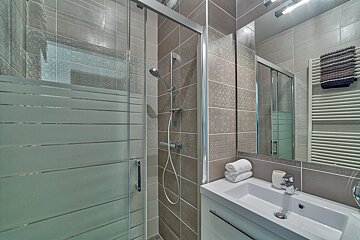 A bathroom with a sliding glass shower door and a sink