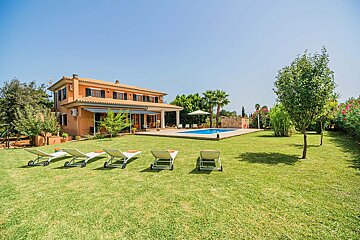 Lawn chairs in front of a large house with a pool