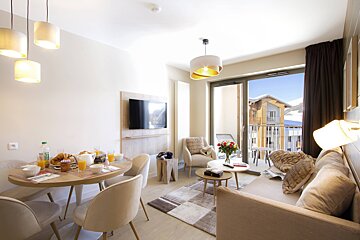 A living room with a table and chairs and a flat screen tv