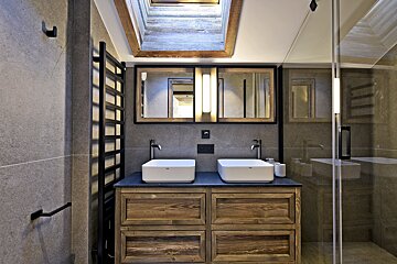 A bathroom with two sinks and a skylight above them