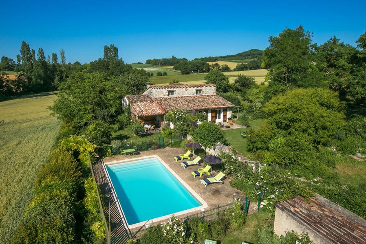 An aerial view of a house with a large swimming pool