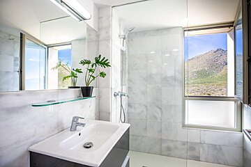 A bathroom with a sink and a window with a mountain in the background
