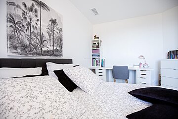 A bedroom with a large painting on the wall above the bed