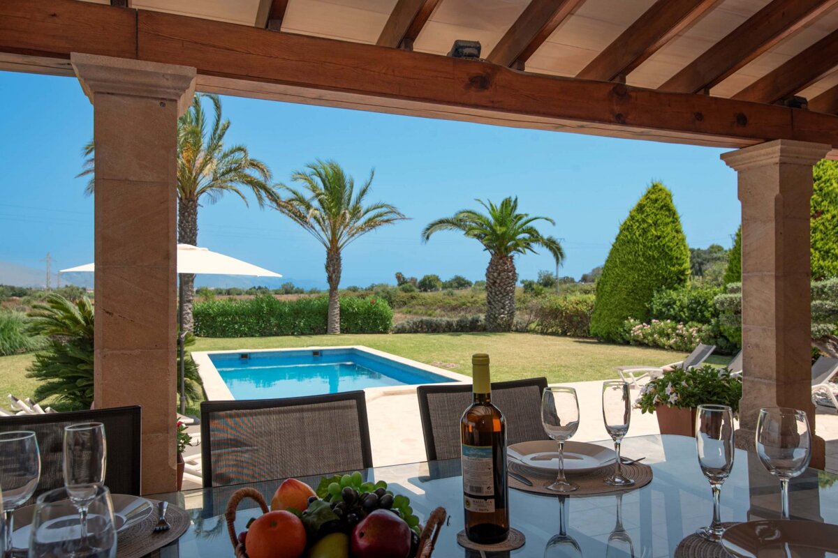 A bottle of wine sits on a table in front of a pool