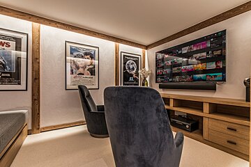 A room with two chairs and a tv with a poster for jaws on the wall
