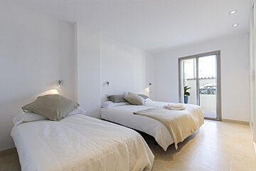 A bedroom with two beds and a sliding glass door