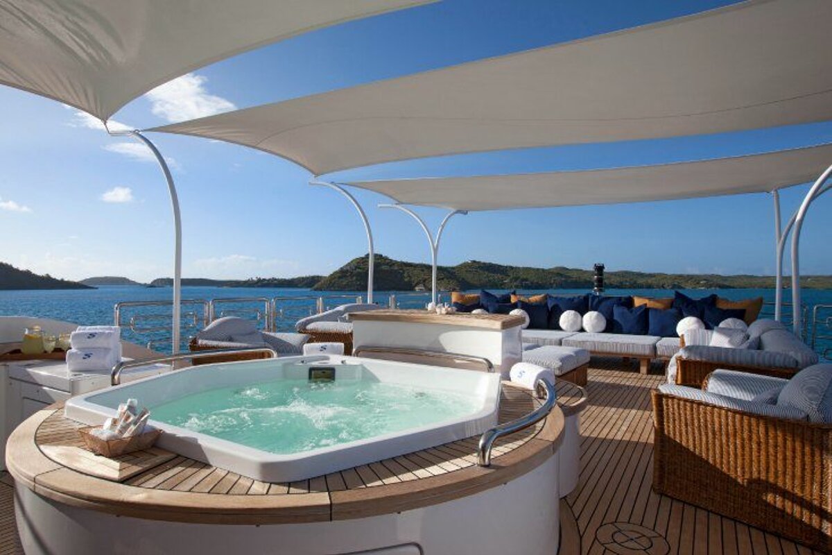 A jacuzzi on the deck of a boat with a blue sail