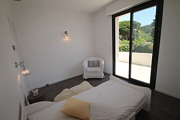 A bedroom with a bed a chair and a sliding glass door