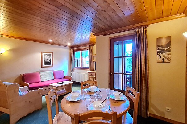 A living room with a table and chairs and a pink couch
