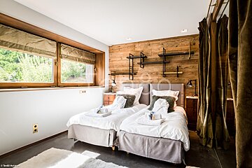A bedroom with two beds and a wooden wall