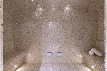 A mosaic tiled room with two towels on the benches