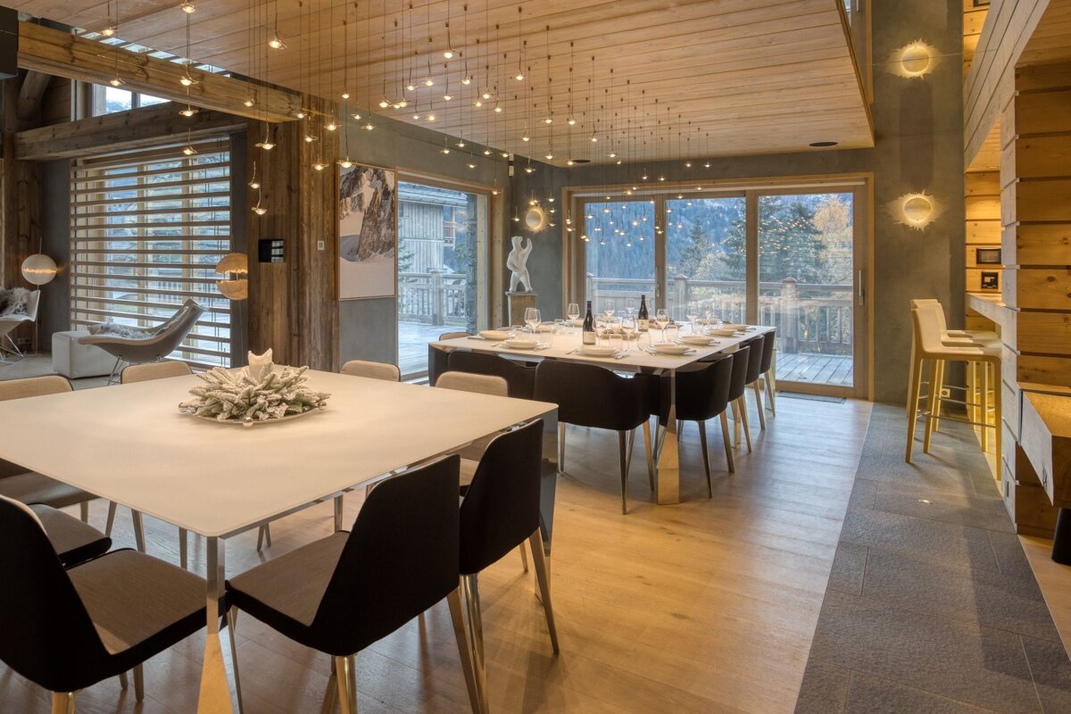 A dining room with a long white table and black chairs