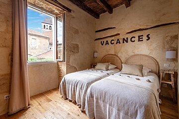 A bedroom with two beds and a wall that says vacances