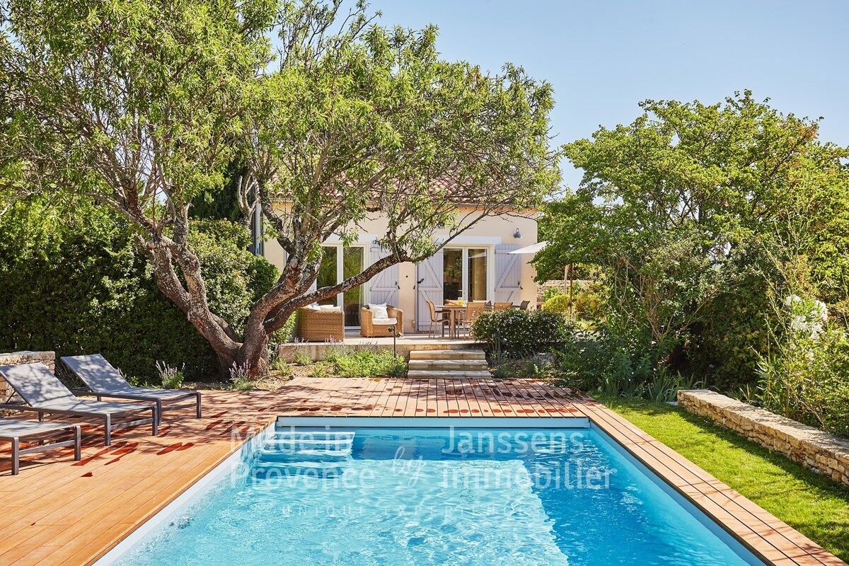 A large swimming pool in front of a house that says janssens immobilier