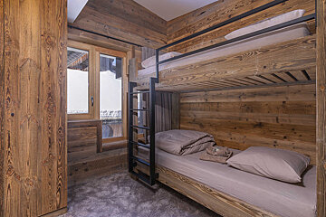 A bunk bed in a wooden room with a window