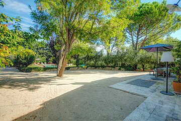 A patio area with umbrellas and chairs and a pool in the background