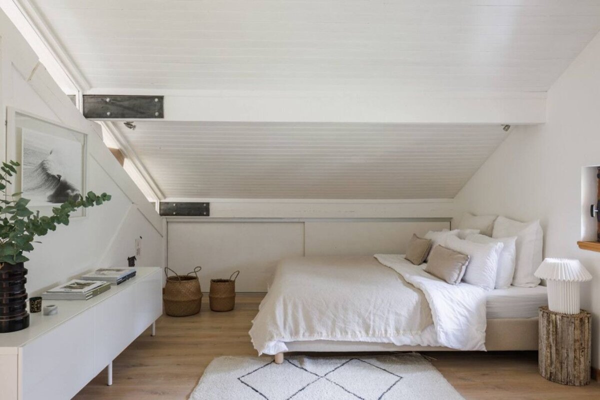 A bedroom with white walls and a white bed