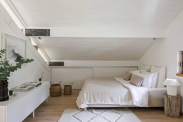 A bedroom with white walls and a white bed