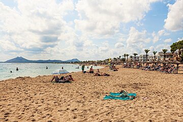 A beach with a lot of people and a blue umbrella