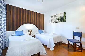 A bedroom with two twin beds and a chair