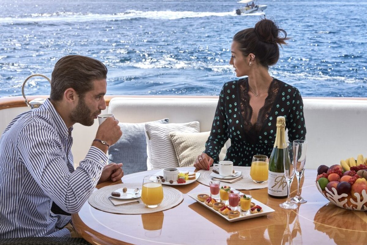 A man and woman sit at a table with a bottle of ap champagne