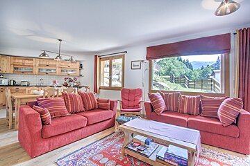 A living room with two red couches and a table with a game of scrabble on it