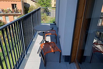 A balcony with two orange chairs and a table