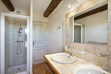 A bathroom with two sinks and a walk in shower