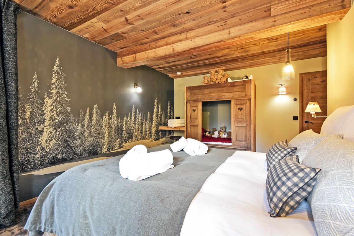 A bedroom with a painting of trees on the wall