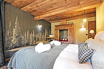 A bedroom with a painting of trees on the wall
