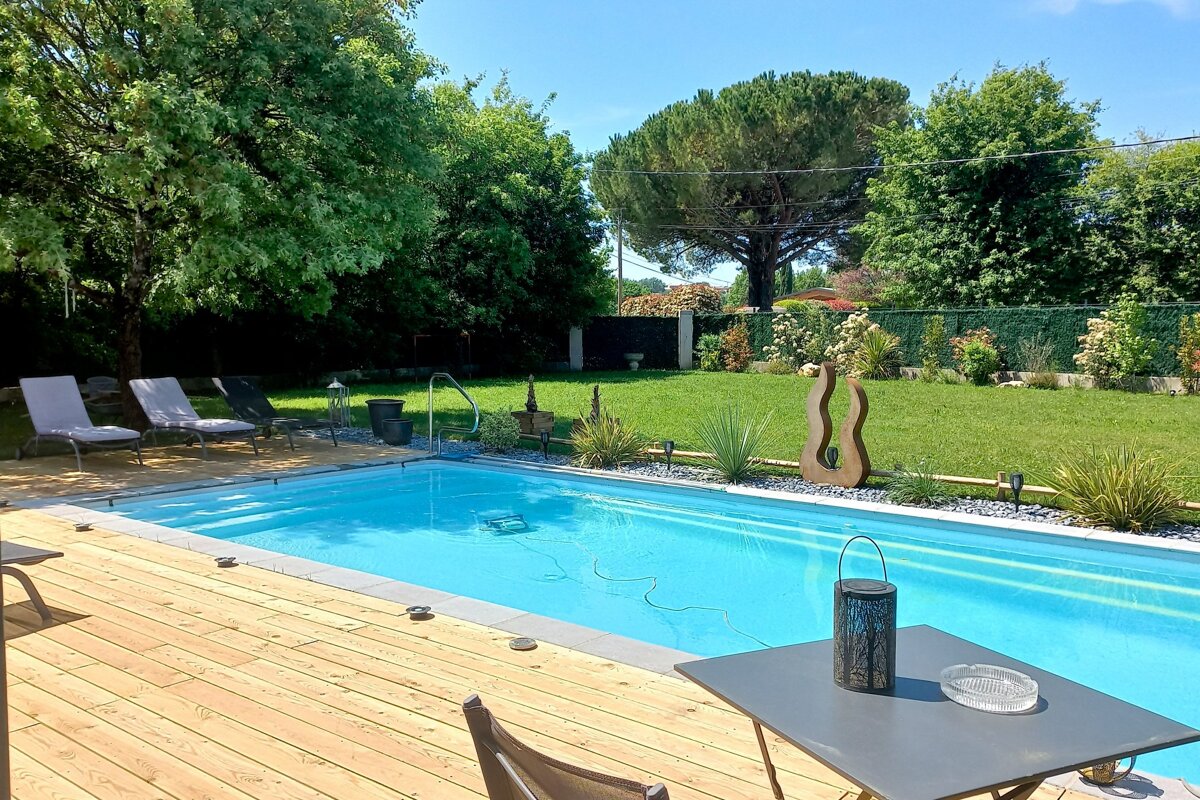 A large swimming pool is surrounded by a wooden deck