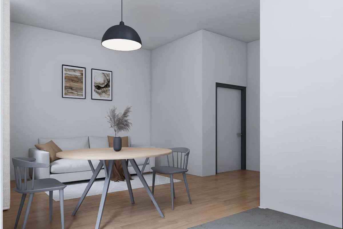 A modern, minimalist dining and living area features a round wooden table with gray chairs, a white sofa, abstract art, and a black pendant light.