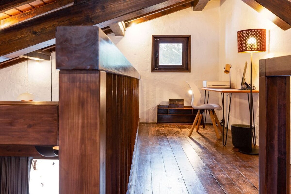 A wooden staircase leads to a room with a desk and chair