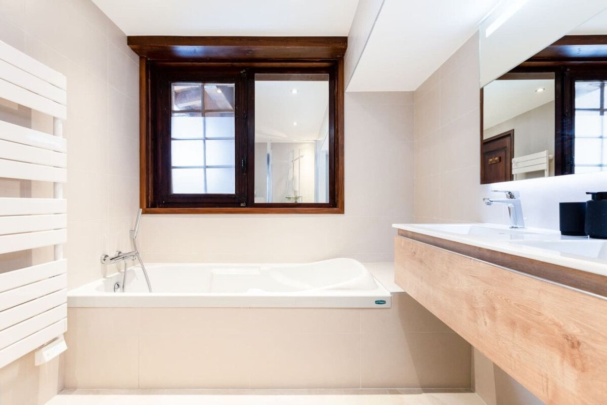 A bathroom with a tub and a sink and a window