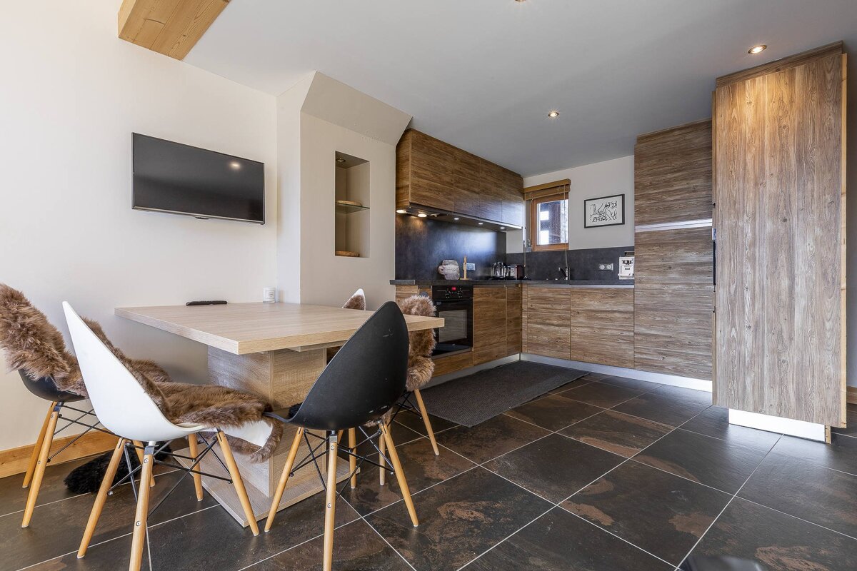 A kitchen with a table and chairs and a flat screen tv