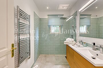A bathroom with green tiles and a towel rack by janssens immobilier