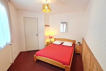 A bedroom with a red bed and two nightstands