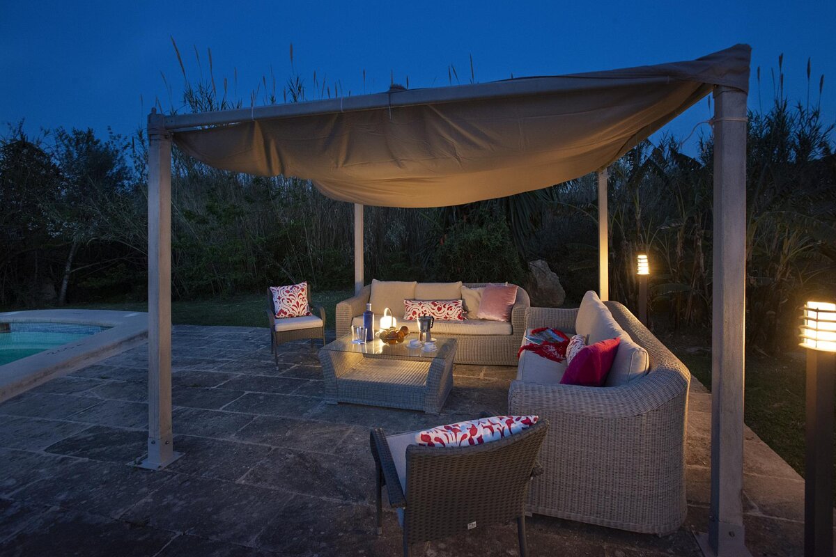 A patio area with a couch and chairs under a canopy