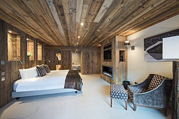 A bedroom with a large bed and a fireplace