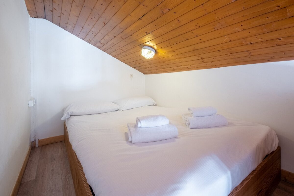A bedroom with a wooden ceiling and a bed