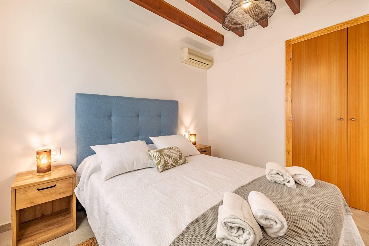 A bedroom with a blue headboard and towels on the bed