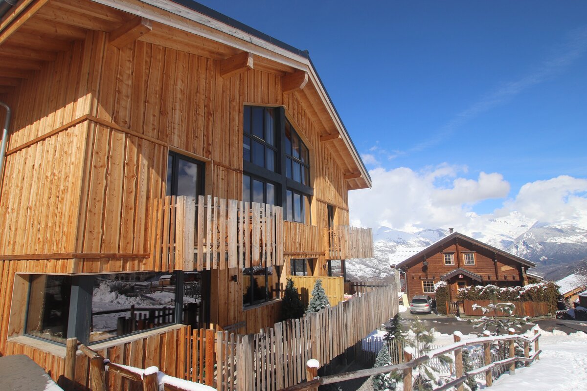 A wooden house with a car parked in front of it